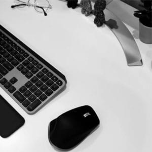 Wireless computer mouse and keyboard on a sleek white desk, ideal for professionals and remote work setups.